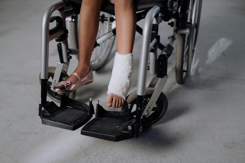 A close-up of a young girl's bandaged leg in a wheelchair, highlighting recovery.